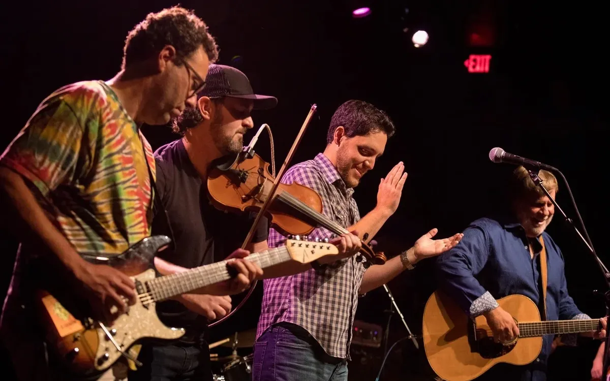 George Dunham and the Bird Dogs on stage with guitars and a fiddle