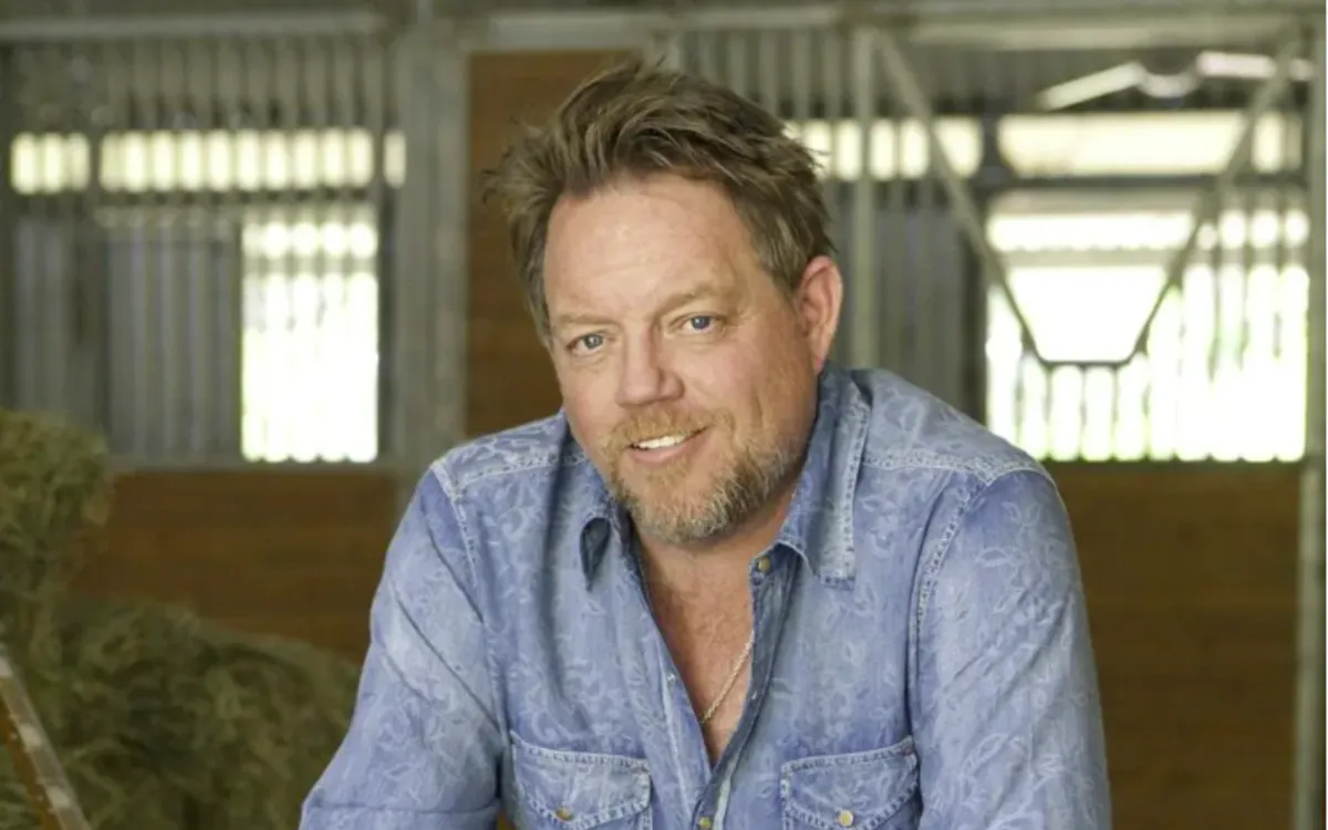 Pat Green in a denim shirt, smiling in a barn doorway